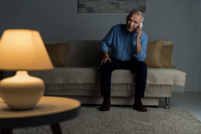 Elderly Man In Living Room Talking On Phone