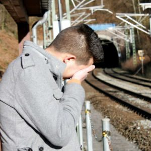 Teenage boy crying beside a railway station