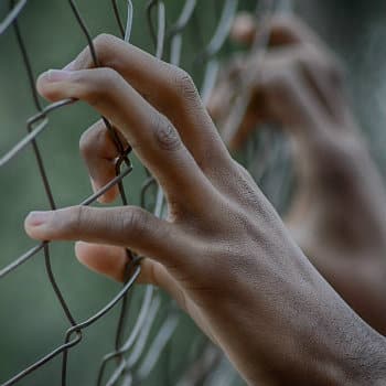 hands holding prison fence