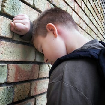 sad boy leaning against wall