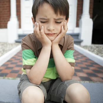 upset young boy sitting outside