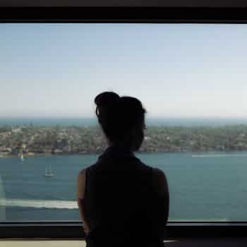 woman looking out window at water